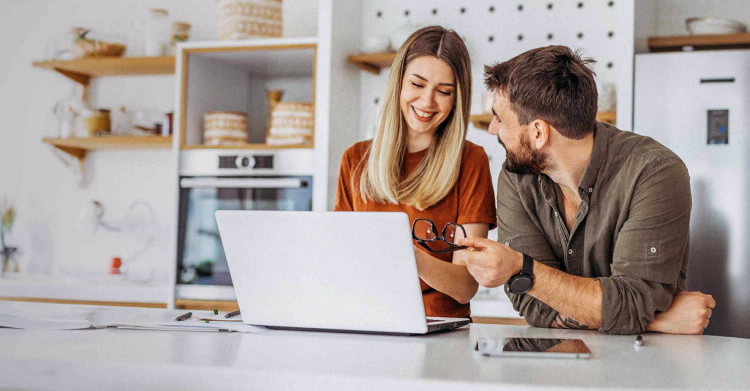 BPI Destino PPR 2060. Casal jovem sorridente a realizar uma simulação para a reforma num portátil.
