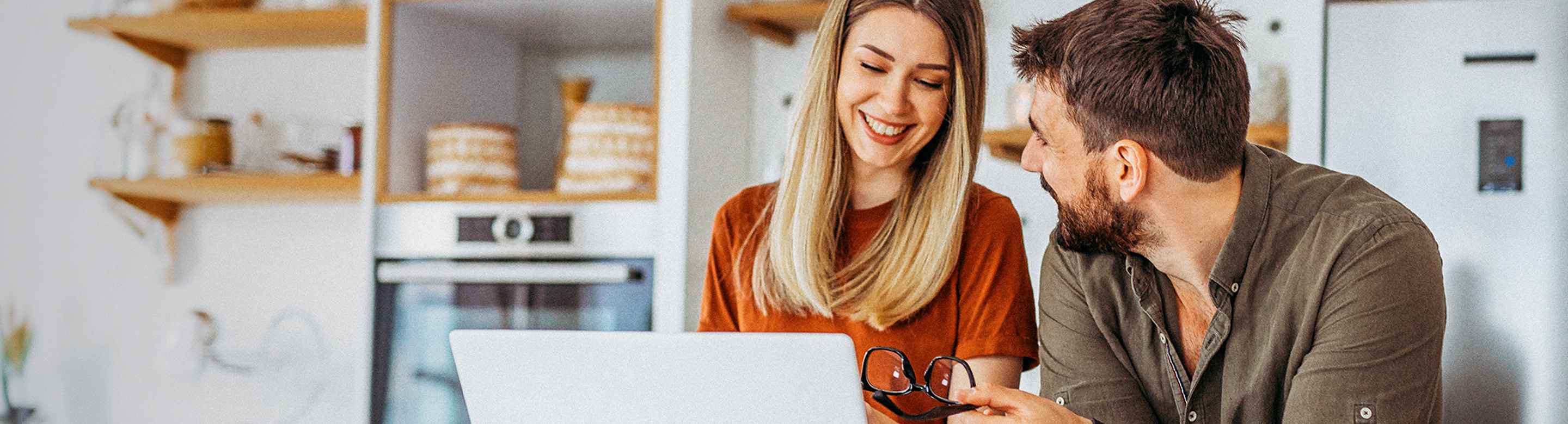 BPI Destino PPR 2060. Casal jovem sorridente a realizar uma simulação para a reforma num portátil.